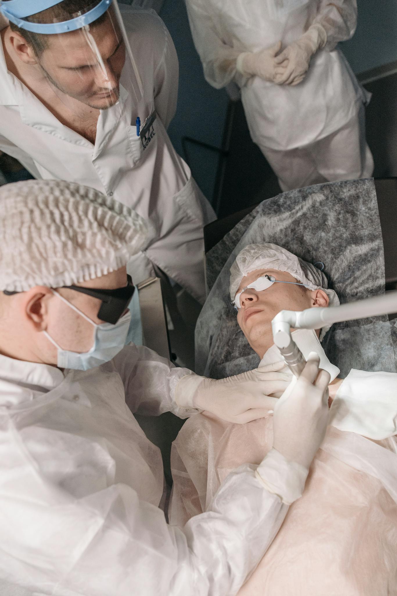 Doctors performing a medical laser procedure in a sterile clinic environment.